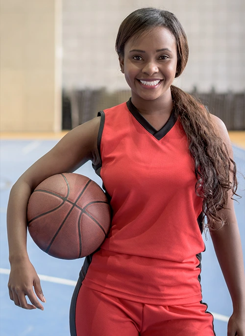 Female basketball player in red uniform holding a ball